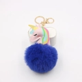 Close-up of fluffy blue pompom unicorn keychain with gold clasp on white stand - Sapphire Blue
