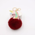 Close-up of pink leather unicorn pendant with fluffy red faux fur pompom and gold key ring - Burgundy