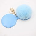 Close-up of light blue plush pompom keychain with golden metal chain and silicone tag - Light Blue