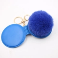Close-up of royal blue fluffy pompom keychain with round mirror case and gold metal clasp - Sapphire Blue