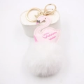 Détail du porte-clés cygne en cuir rose avec pompon blanc et mousqueton doré brillant - Blanc
