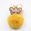 Dettaglio di un portachiavi a testa di orso bruno con pompon giallo e gancio dorato - Arancione