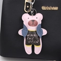 Detail eines rosa Lederbären-Anhängers mit Winnie-Schriftzug an einer schwarzen Handtasche - Rosa