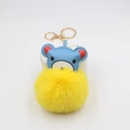 Macro shot of a cute blue leather bear keychain with a bright yellow fluffy pompom - Yellow