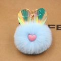 Dettaglio del portachiavi a pompon azzurro con orecchie iridescenti e cuore rosa morbido - Azzurro