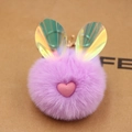 Dettaglio di un portachiavi a pompon viola con orecchie da coniglio laser e cuore rosa - viola taro