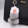 Cute sleeping doll pom pom keychain hanging on a black textured leather handbag - Sleeping Doll / Light Gray