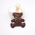 Close-up of brown leather bear keychain with red green plaid bow and golden metal ring - Bear Charm / Brown