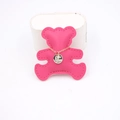 Macro shot of gold fine chain necklace with silver round pendant on a pink bear card - Rose Red