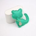 Close-up of golden necklace with engraved rhinestone pendant on green cat-shaped leather pad - Green