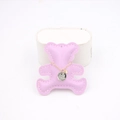 Detail showing a gold chain necklace with embossed pendant on a pink bear-shaped leather plate - Taro Purple