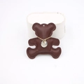 Detail of a bicolor coin pendant with engraved text and zircon on a brown leather bear - Brown