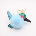 Close-up of sky blue faux fur hummingbird keychain with metallic gold clasp and leather wings - Light Blue