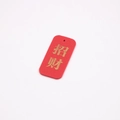 Macro detail of red lucky charm with gold Zhaocai engraving and smooth edges - Beckoning Wealth