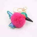 Detail van een kleurrijke kolibrie sleutelhanger met een felroze pluchen pompon - Rozerood