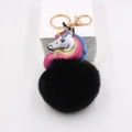 Close-up of black faux fur pompom keychain with golden clip and unicorn charm - Black