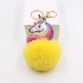 Detail of yellow plush pompom keychain with printed unicorn leather charm and gold clasp - Yellow