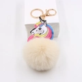 Detailed view of plush unicorn keychain with beige faux fur ball and gold metal clasp - Off White