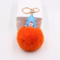 Close-up of fluffy orange faux fur pom pom with blue snowman charm and golden metal clasp - Red