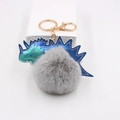 Détail du porte-clés pompon gris avec dinosaure irisé et anneau en métal doré brillant - Gris clair