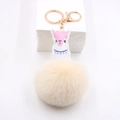 Détail du charme d'alpaga en cuir rose avec pompon beige et fermoir mousqueton doré - Blanc Cassé