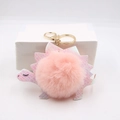 Close-up of pink iridescent dinosaur keychain with soft faux fur pompom and gold clasp - Pink