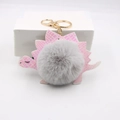 Détail d'un porte-clés dinosaure en similicuir rose avec pompon gris en fourrure - Gris clair