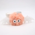 Detailed close-up of the plush pink monster keychain with white bat wings and cartoon eyes - Pink
