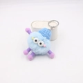 Detail of blue plush monster keychain with purple spring limbs and a blue knit hat - Light Blue