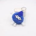 Detailed macro view of the fluffy blue monster keychain with a blue knitted hat and spring limbs - Royal Blue