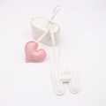 Detail eines rosa Lederherzens und weißen Buchstaben-H-Anhängers mit Ziernähten - Herz Und Buchstabe H Stil / Rosa + Weiß