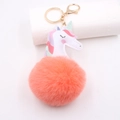 Detailed macro view of unicorn plush ball keychain with pink fur and golden metal clasp - Gold Keychain / Orange Red