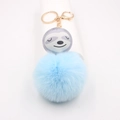Gros plan d'un porte-clés pompon bleu ciel avec un adorable visage de paresseux - Bleu clair