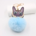 Dettaglio di un portachiavi a mostro con pompon blu e ali di pipistrello in pelle viola - Azzurro