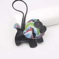 Dettaglio di un ciondolo a forma di animale in pelle nera con motivi graffiti colorati - Leone