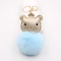 Vue détaillée du porte-clés pompon en fausse fourrure bleue avec charme d'ours doré - Bleu clair