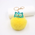 Détail macro du porte-clés hibou en peluche avec pompon jaune et fermoir mousqueton doré - Porte-clés Doré / Jaune