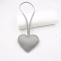 Detail of grey heart leather bag charm with knot strap and visible stitching on white base - Gray