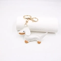 Close-up of white PU leather dachshund keychain with golden lobster clasp and brown stitching - White