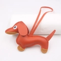 Close-up of leather dachshund bag charm with fine stitching on white cylinder - Hanging Organizer Style / Orange Red