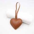 Close-up of brown heart-shaped leather bag charm with detailed stitching and strap - Coffee