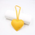 Close-up of heart-shaped leather bag charm in lemon yellow with litchi grain texture - Yellow