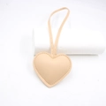 Close-up of beige heart-shaped leather bag charm with litchi grain and hanging strap - Flesh Pink