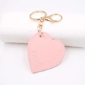 Nahaufnahme von pinkfarbenem Herz-Schlüsselanhänger aus Leder mit LOVELY MOMENTS Prägung - Rosa
