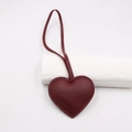 Macro detail of dark burgundy heart leather charm with lychee texture and stitching - Burgundy
