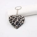 Macro shot of leopard print heart keychain with silver metal ring on white stand - Off-white