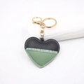 Detail van hartvormige leren sleutelhanger met contraststiksels en gouden metalen haak - Groen & Zwart