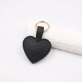 Dettaglio del portachiavi a cuore in pelle nera con grana litchi e anello in metallo oro - Cuore Magnetico / Nero