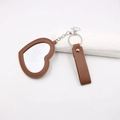Détail d'un miroir de poche en forme de cœur en cuir marron avec porte-clés en métal argenté - Cœur / Marron