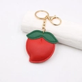 Détail du porte-clés fraise en cuir rouge avec feuilles vertes et fermoir mousqueton doré - Style Fraise / Rouge